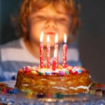 enfant qui souffle sur les bougies de sont gâteau d'anniversaire