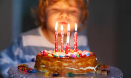 enfant qui souffle sur les bougies de sont gâteau d'anniversaire