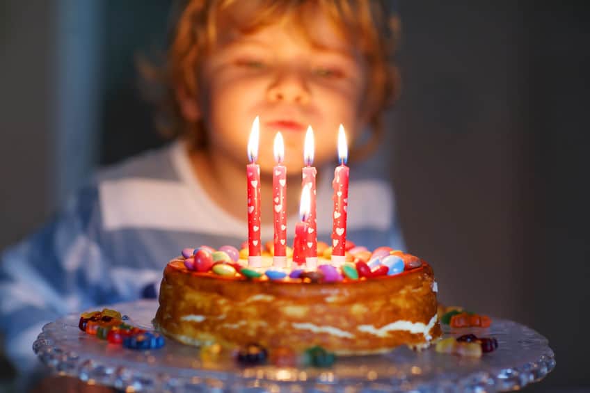 enfant qui souffle sur les bougies de sont gâteau d'anniversaire