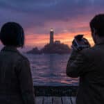 Silhouetted figures on a pier watch a distant lighthouse at sunset, with purple, blue, and orange sky reflections on the water.
