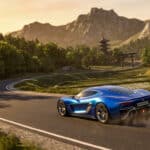 A vibrant metallic electric blue hypercar speeds on a winding road in a lush Japanese mountain landscape at golden hour, with a pagoda and torii gate.